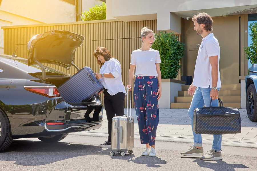 Fahrgäste mit Gepäck steigen bei Taxi Bastone ein